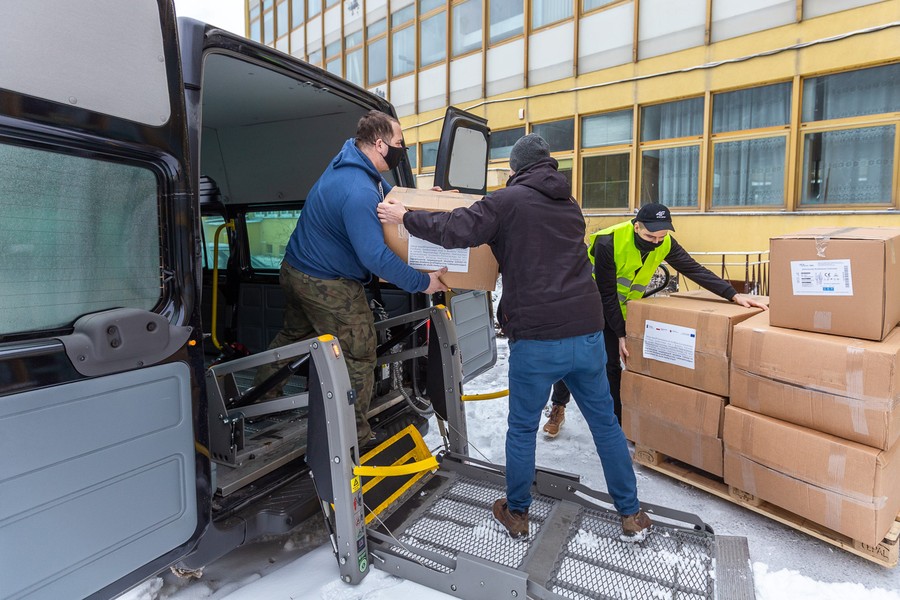 Rozpakowywanie kartonów z kombinezonami z busa transportowego, fot. Szymon Zdziebło/tarantoga.pl dla UMWKP
