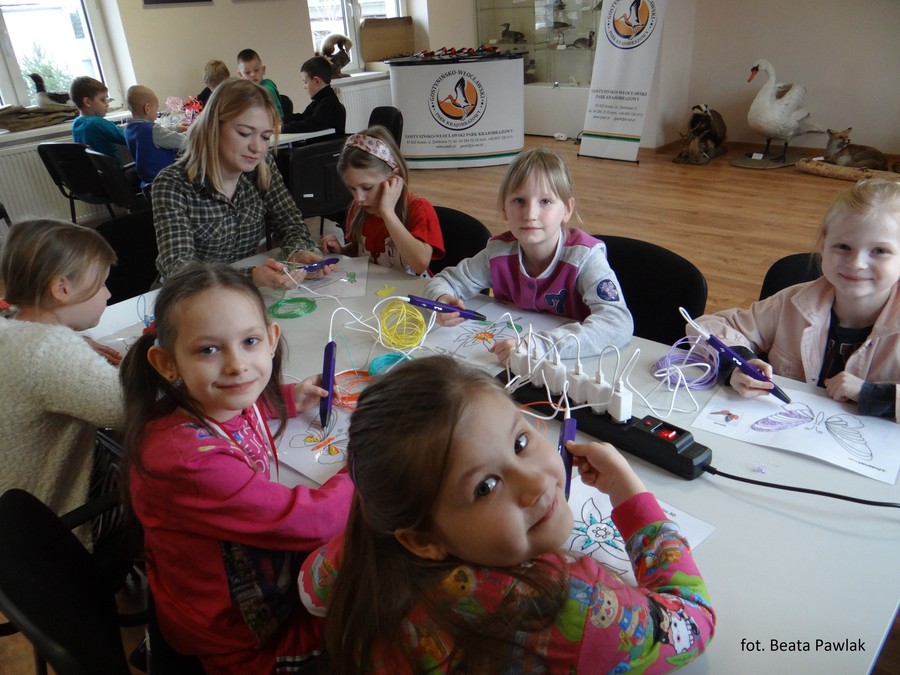 Zdjęcie przedstawia dziewczynki oraz pracownika parku podczas rysowania długopisami 3D