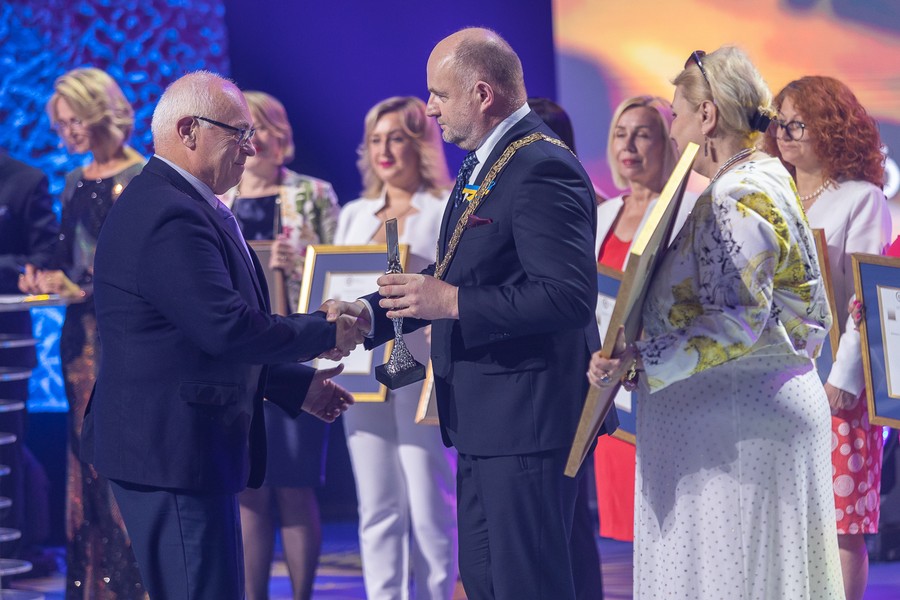 Marszałek Piotr Całbecki wręcza nagrodę Adamowi Sczanieckiemu podczas gali Nagród Marszałka w 2023, fotografia autorstwa Mikołaj Kuras dla Urzędu Marszałkowskiego Województwa Kujawsko-Pomorskiego