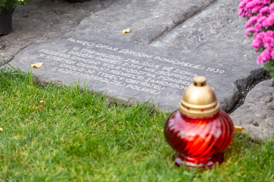 Marszałek Piotr Całbecki i towarzyszące mu osoby zapalają znicze pod pomnikiem Pamięci Ofiar Zbrodni Pomorskiej 1939, fot. Szymon Zdzieblo/tarantoga.pl dla UMWKP