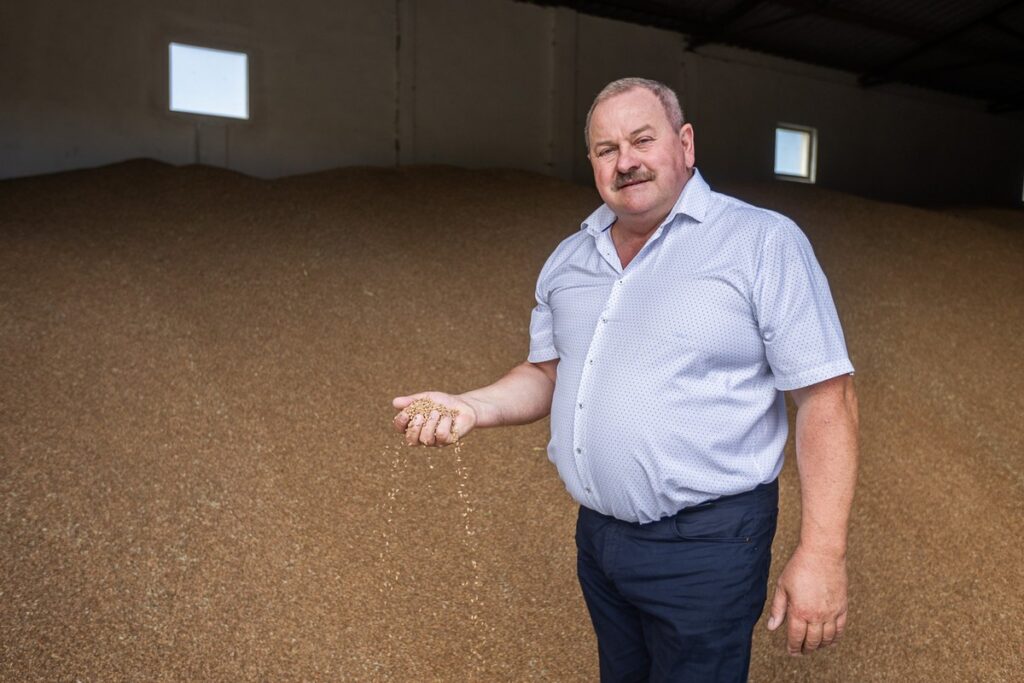 Kazimierz Kurzyński trzymający w garści ziarna zboża, fot. Szymon Zdziebło/tarantoga.pl