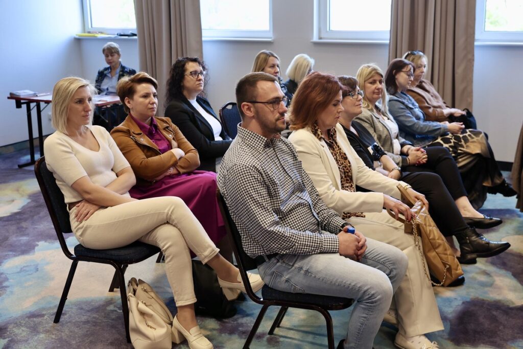 Zdjęcie ludzi na krzesłach – uczestnicy seminarium, przedstawiciele Powiatowych Centrów Pomocy Rodzinie – seminarium „Administracja publiczna wobec zjawiska przemocy domowej – analiza dostępnych narzędzi oddziaływań” fot. Andrzej Goiński