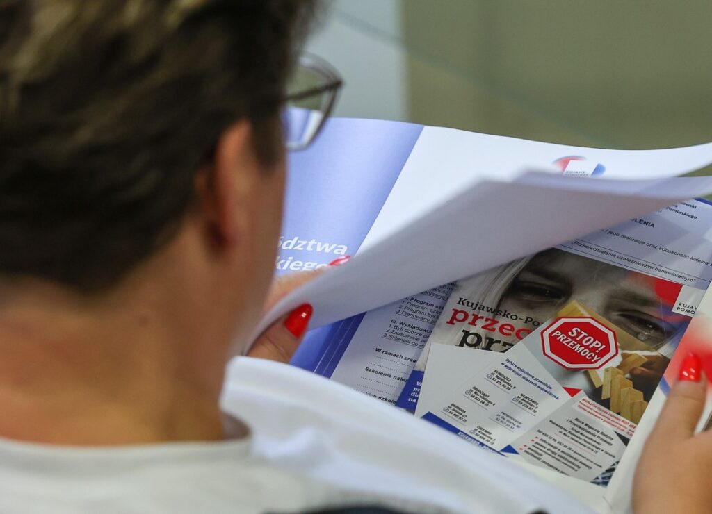 Pani patrząca na materiały informacyjne, ulotki o tematyce przemocy domowej