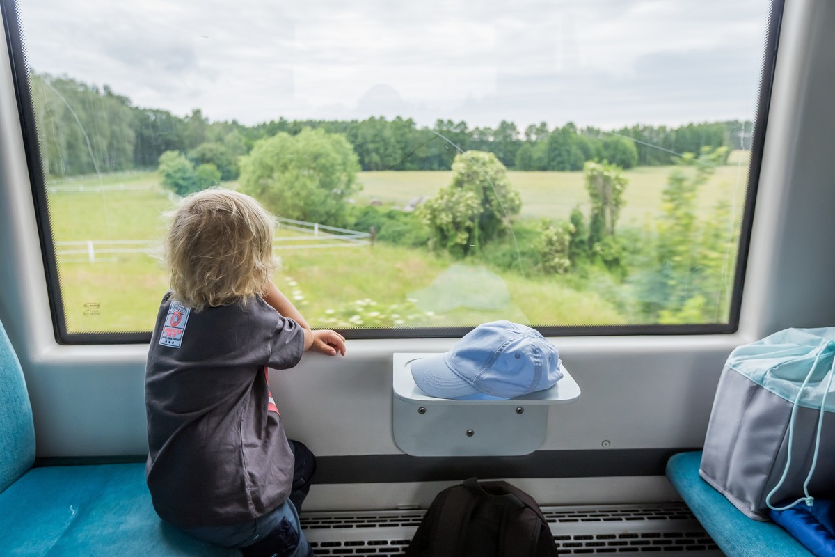 Dziecko siedzące w przedziale pociągu wpatrzone w krajobraz za oknem