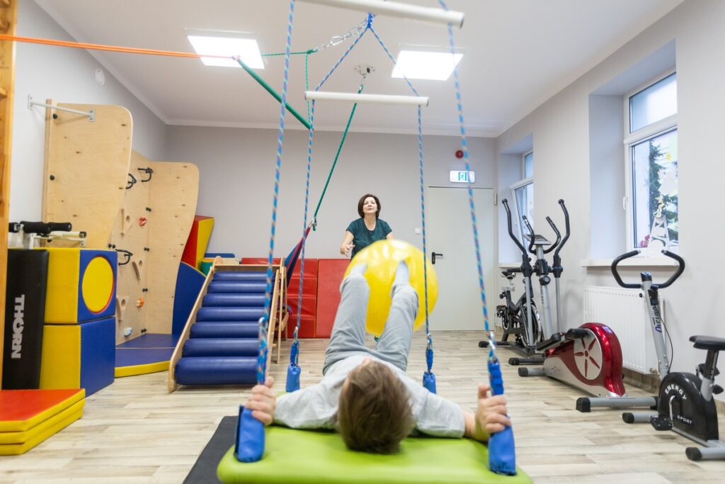 Osoba ćwicząca w sali rehabilitacyjnej