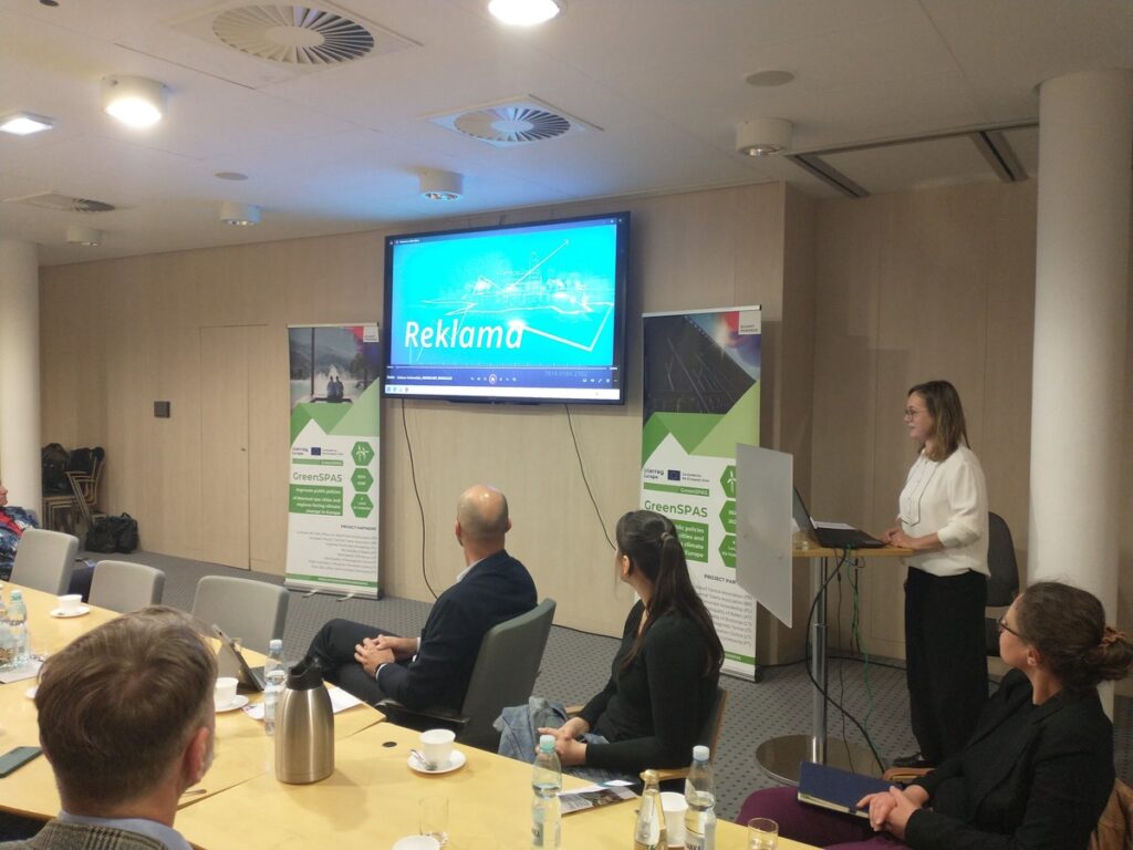 Uczestnicy spotkania skupieni na prezentacji siedząc przy stole