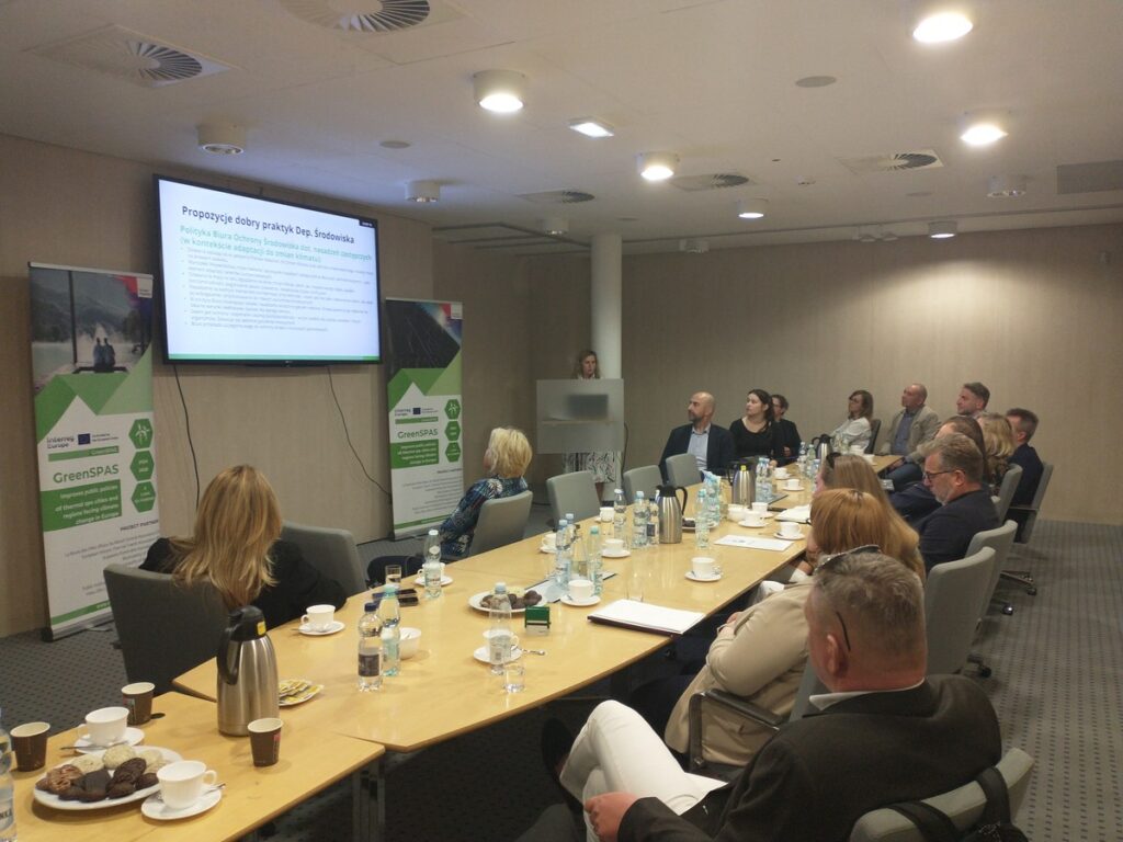 Uczestnicy spotkania skupieni na prezentacji siedząc przy stole